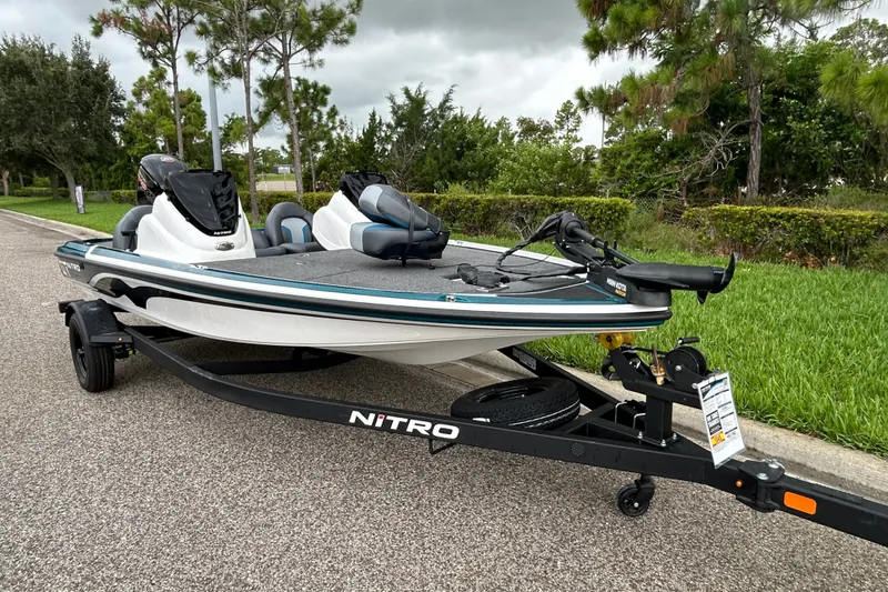 Slide: The Image of 2027 Nitro Z17 boat on trailer, parked roadside with lush greenery background. - 7