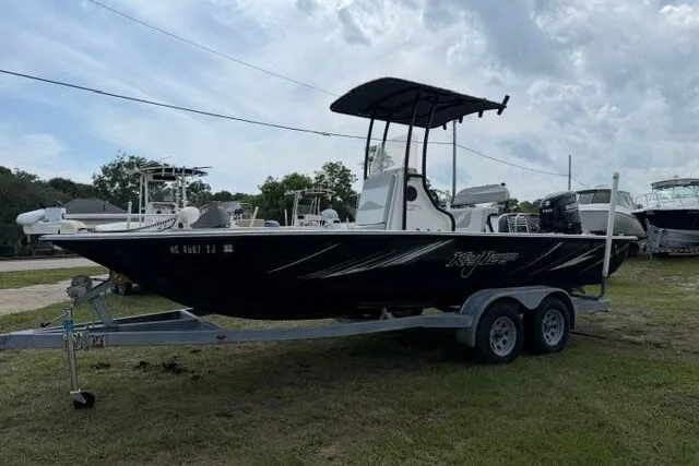 Slide: The Image of 2018 Key Largo 220 Bay boat on trailer, parked outdoors under cloudy sky. - 2