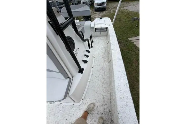 Slide: The Image of 2018 Key Largo 220 Bay boat interior with seating and console, parked on grass. - 11