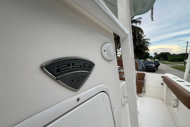 Slide: The Image of 2015 Tidewater 250 CC Adventure boat, side view with emblem, parked on street. - 54