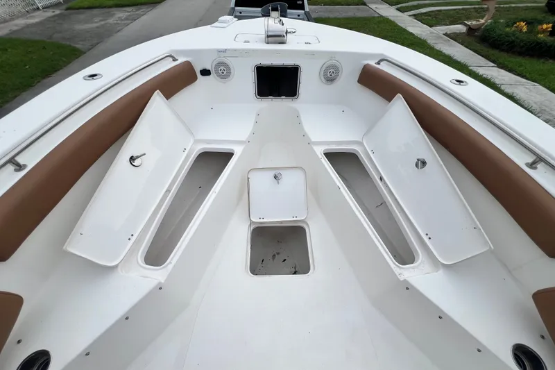 Slide: The Image of 2015 Tidewater 250 CC Adventure boat interior with open storage compartments and cushioned seating. - 60