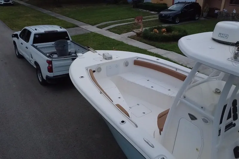Slide: The Image of 2015 Tidewater 250 CC Adventure boat towed by a white pickup truck on a suburban street. - 77