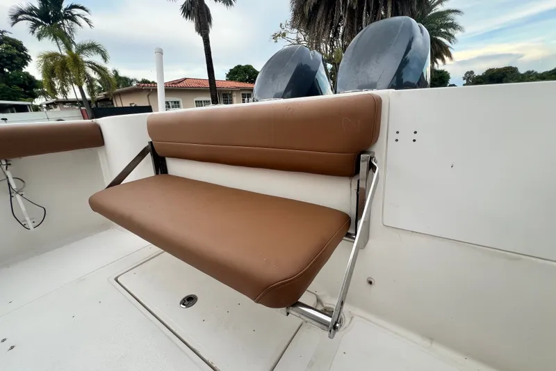 Slide: The Image of Brown bench seat on 2015 Tidewater 250 CC Adventure boat, surrounded by palm trees. - 27