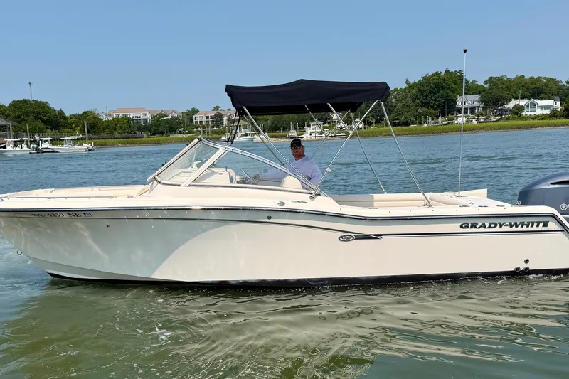 Slide: The Image of 2017 Grady-White Freedom 235 boat on water, with canopy and driver, near shoreline. - 8