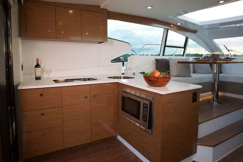 Slide: The Image of Manufacturer Provided Image: Modern kitchen area in 2022 Cruisers Yachts 46 Cantius with wood cabinetry and sleek appliances. - 9