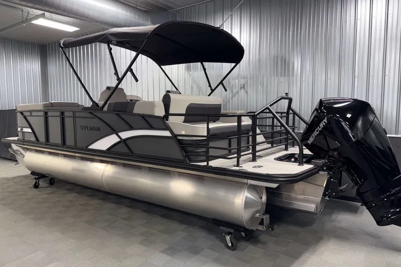 Slide: The Image of 2026 Sylvan L3 CLZ DH Tritoon boat with Mercury engine in a metal garage. - 25