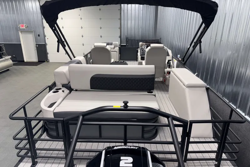 Slide: The Image of 2026 Sylvan L3 CLZ DH Tritoon interior with seating and Mercury engine in a showroom. - 2