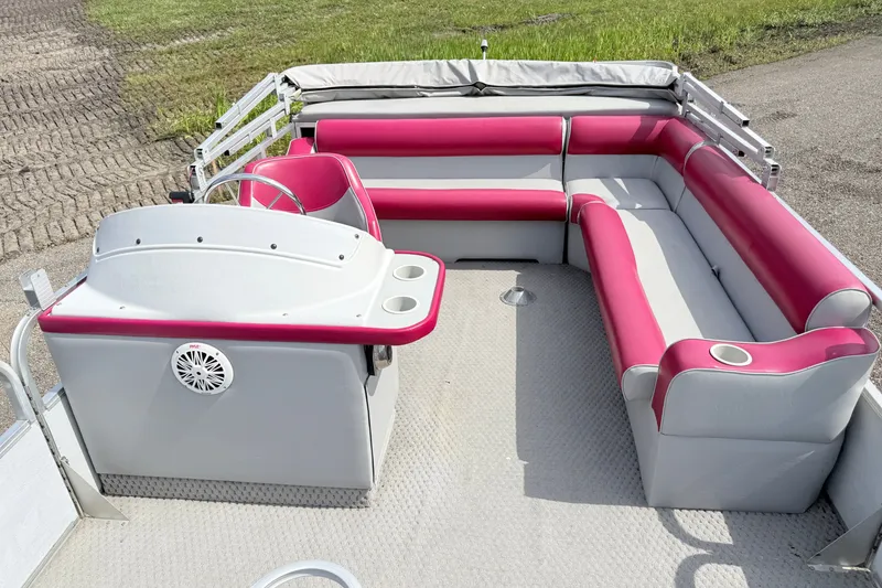 Slide: The Image of 1994 Crest 22 pontoon boat interior with pink and gray seating, steering console, and cup holders. - 10