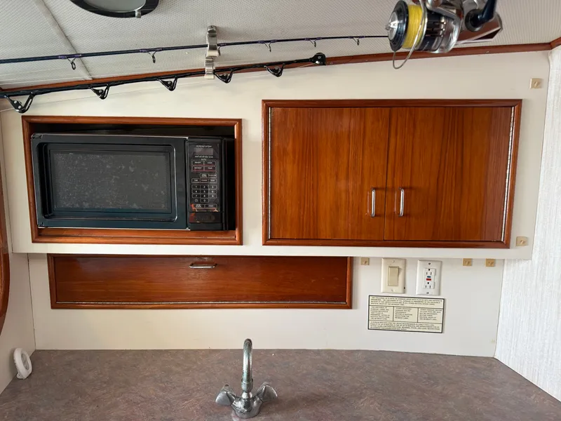 Slide: The Image of Interior of a boat galley with a microwave, wooden cabinets, and a faucet. - 36
