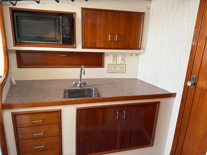 Slide: The Image of Galley area with wooden cabinets, sink, and microwave in a boat. - 35