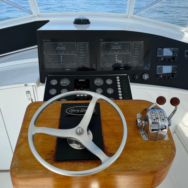 Slide: The Image of The image shows a boat's helm with a wooden steering wheel and modern instruments. - 26