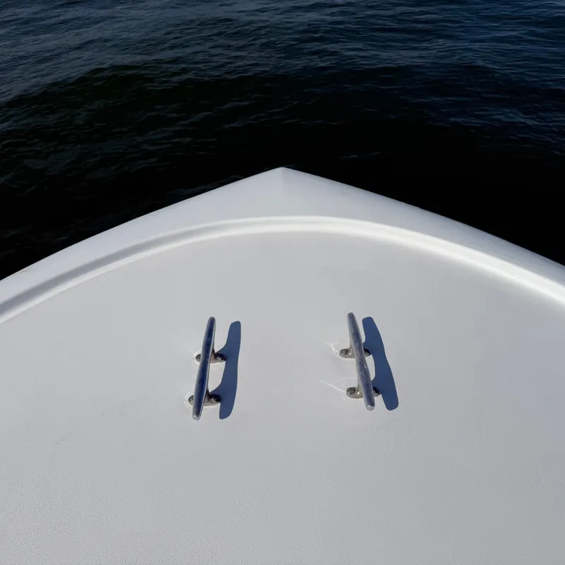 Slide: The Image of The bow of a white boat with two metal cleats, floating on calm water. - 7