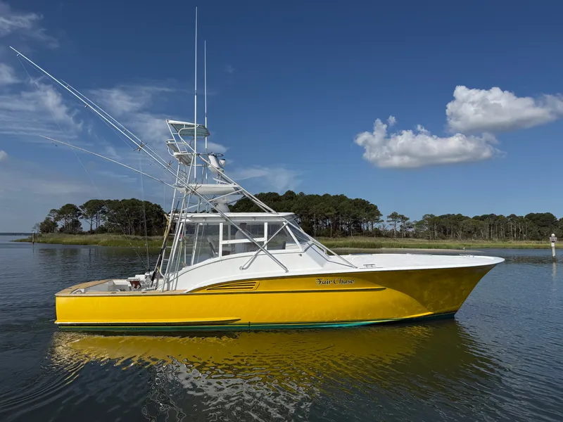 The Image of A yellow boat with an elevated helm station, floating on calm water, surrounded by trees. - 0