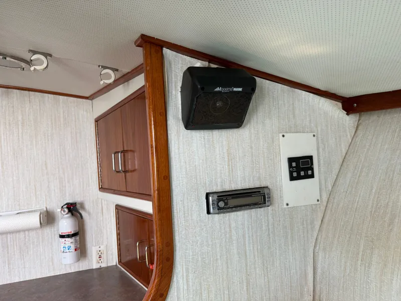 Slide: The Image of Interior of a boat with wooden cabinets, speaker, fire extinguisher, and control panel on the wall. - 38
