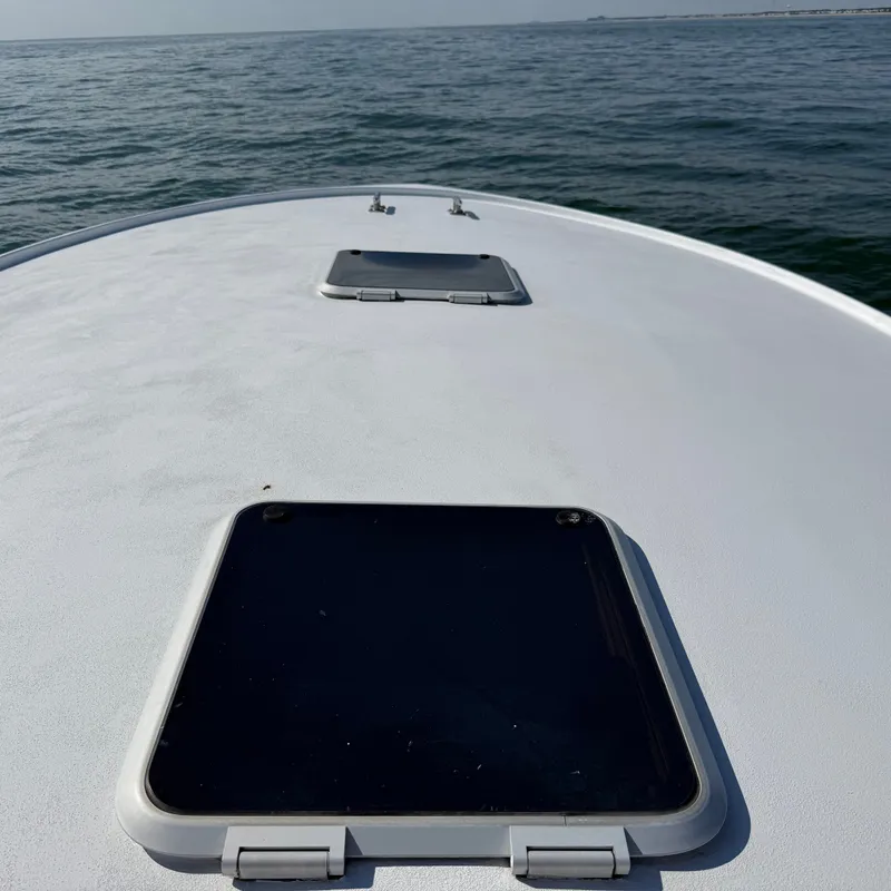 Slide: The Image of The image shows a boat deck with two hatches, cruising on calm waters. - 12