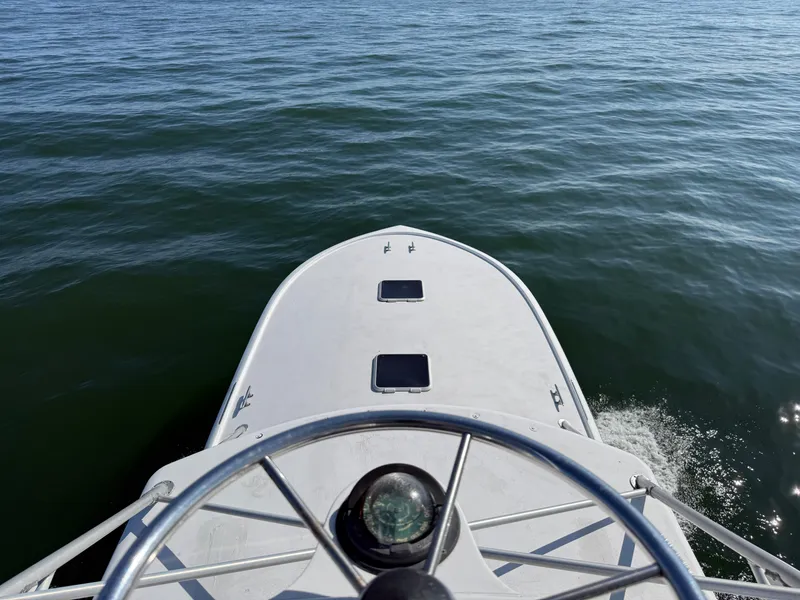 Slide: The Image of The boat is cruising on calm water. The bow is white with two hatches. A compass is visible. - 11