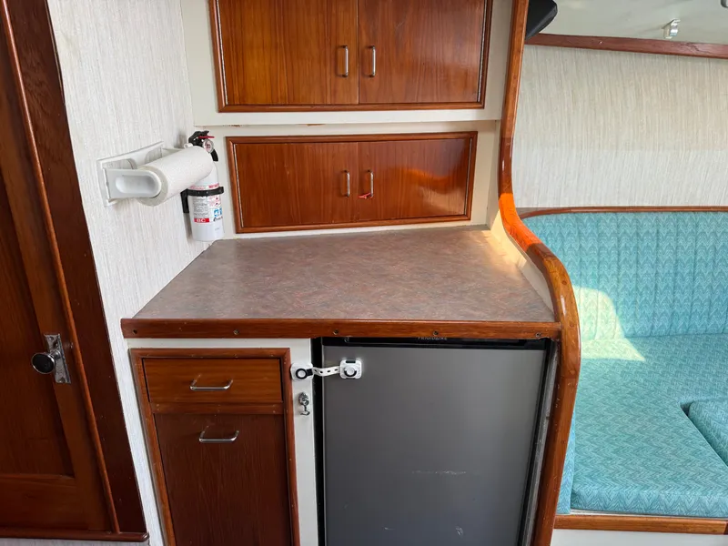Slide: The Image of The boat's interior cabin features a small kitchenette with wooden cabinets and a refrigerator. - 33