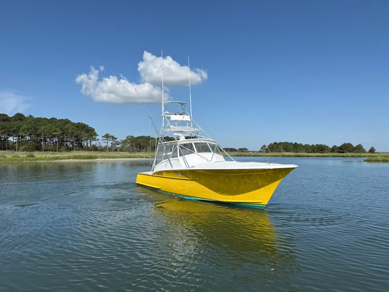Slide: The Image of A yellow boat with a tower navigates calm waters, surrounded by trees and a blue sky. - 1