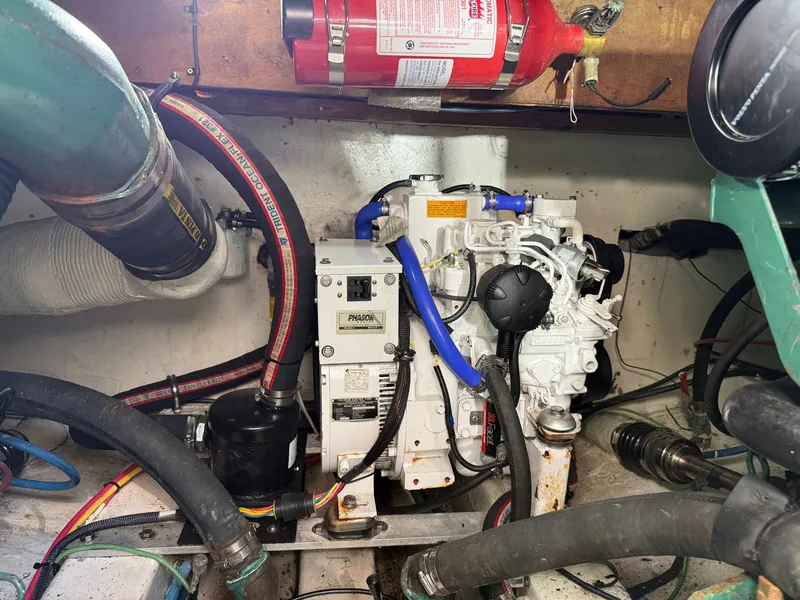 Slide: The Image of An engine room with a white engine, hoses, and a fire extinguisher mounted on the wall. - 47