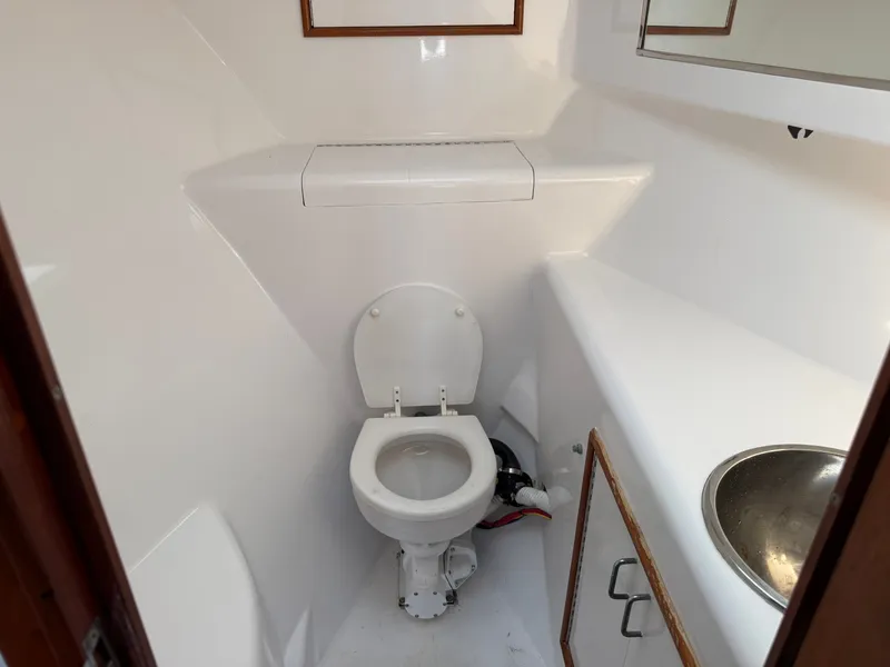 Slide: The Image of The image shows a clean, white bathroom on a boat with a toilet and sink. - 40
