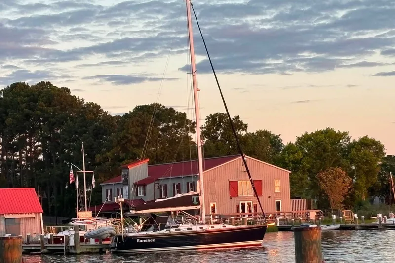 Slide: The Image of Sailboat Tartan 3700 (2005) docked at marina during sunset, surrounded by trees and buildings. - 57