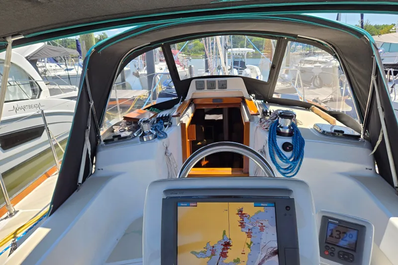 Slide: The Image of Cockpit view of a 2005 Tartan 3700 sailboat with navigation equipment and marina background. - 2