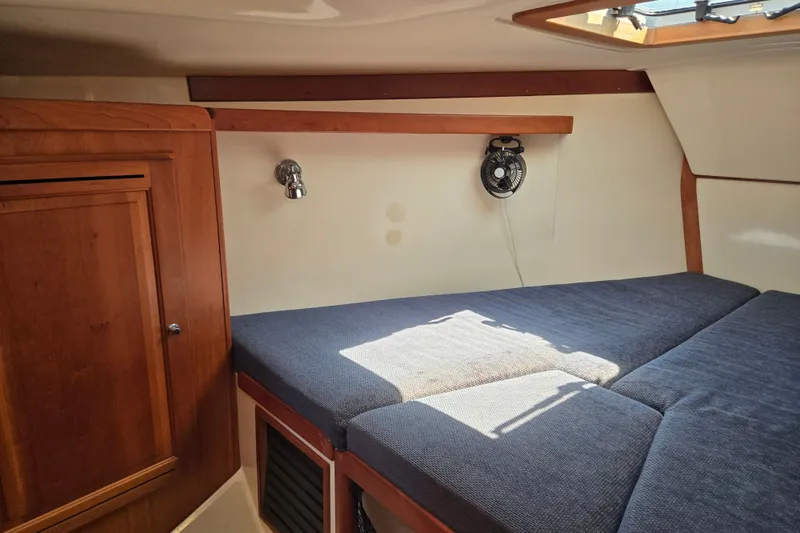 Slide: The Image of Cozy cabin interior of 2005 Tartan 3700 sailboat with wooden cabinetry and blue cushions. - 44