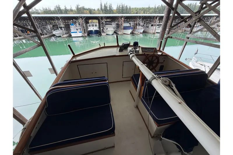 Slide: The Image of 1969 Grand Banks 42 Classic yacht interior with blue seating and wooden helm. - 14