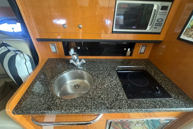 Slide: The Image of 2008 Chaparral Signature 290 boat kitchen with granite countertop, sink, stove, and microwave. - 29
