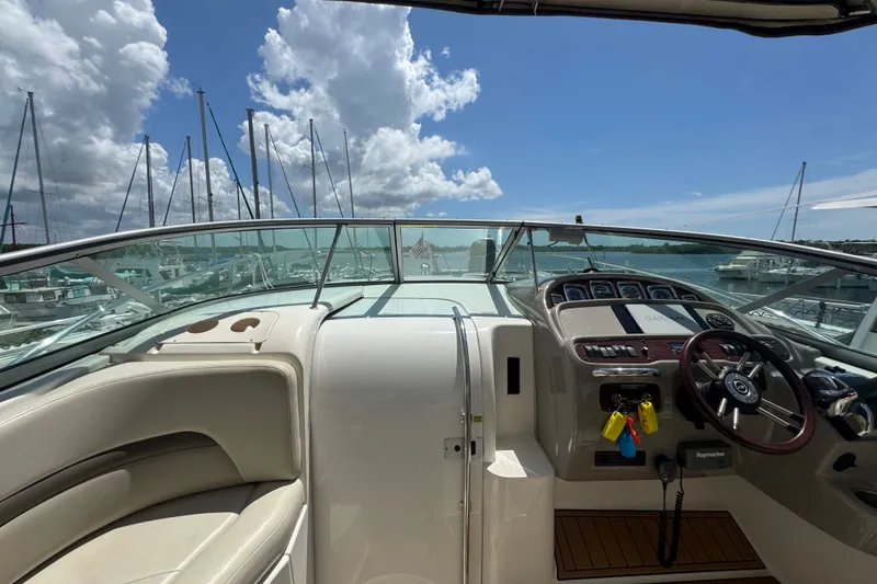 Slide: The Image of 2008 Chaparral Signature 290 boat cockpit with steering wheel, marina view, and clear sky. - 18