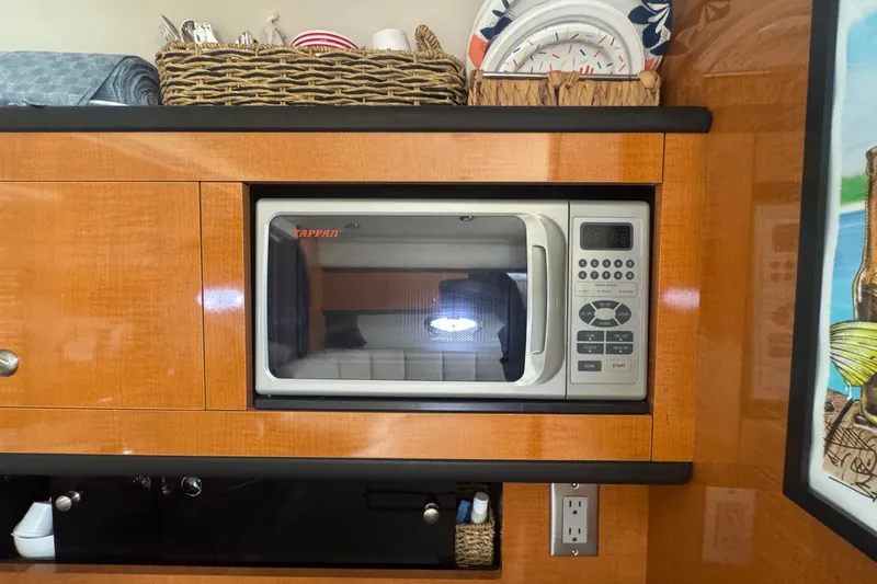 Slide: The Image of 2008 Chaparral Signature 290 interior with microwave, wooden cabinetry, and decorative items. - 32