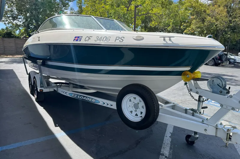 Slide: The Image of 2000 Monterey 190LS Montura boat on trailer in parking lot, surrounded by trees. - 4