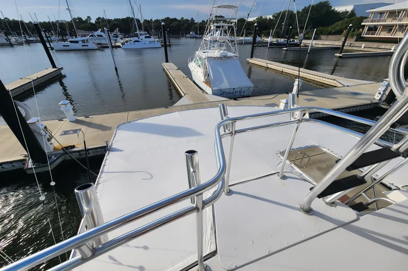 Slide: The Image of 1999 Hatteras 65 Convertible yacht docked at a marina, surrounded by other boats. - 48