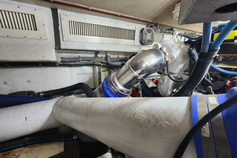 Slide: The Image of Engine room of 1999 Hatteras 65 Convertible yacht with visible exhaust pipes and ventilation. - 76