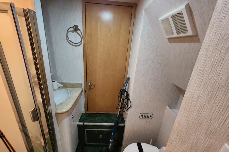 Slide: The Image of Bathroom interior of 1999 Hatteras 65 Convertible yacht, featuring sink and wooden door. - 35