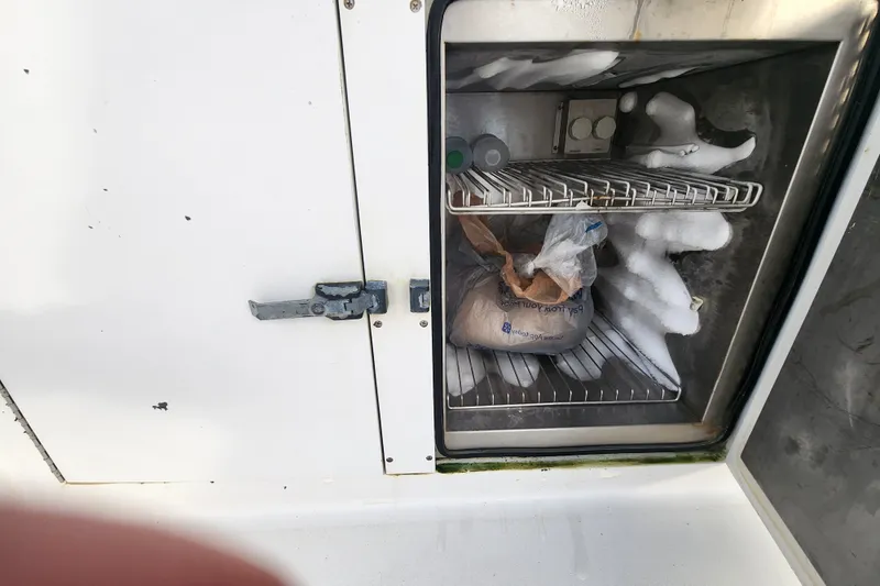 Slide: The Image of Freezer compartment on 1999 Hatteras 65 Convertible boat with ice buildup and stored items. - 65