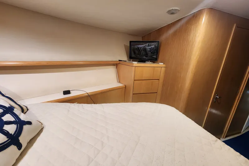 Slide: The Image of Interior of 1999 Hatteras 65 Convertible yacht bedroom with TV and wooden cabinetry. - 24