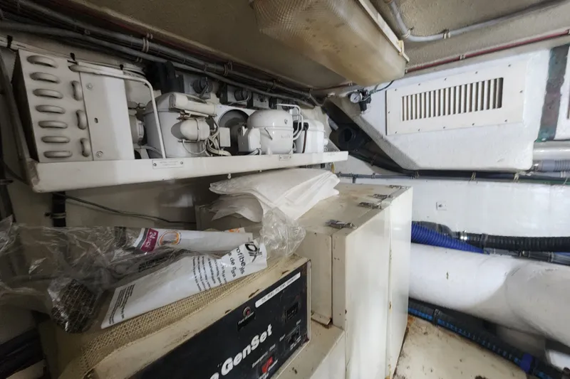 Slide: The Image of Engine room of a 1999 Hatteras 65 Convertible yacht, featuring mechanical equipment and storage. - 75