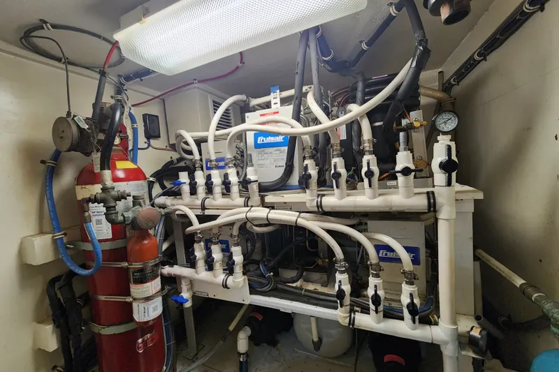 Slide: The Image of Engine room of a 1999 Hatteras 65 Convertible yacht with complex piping and equipment. - 74