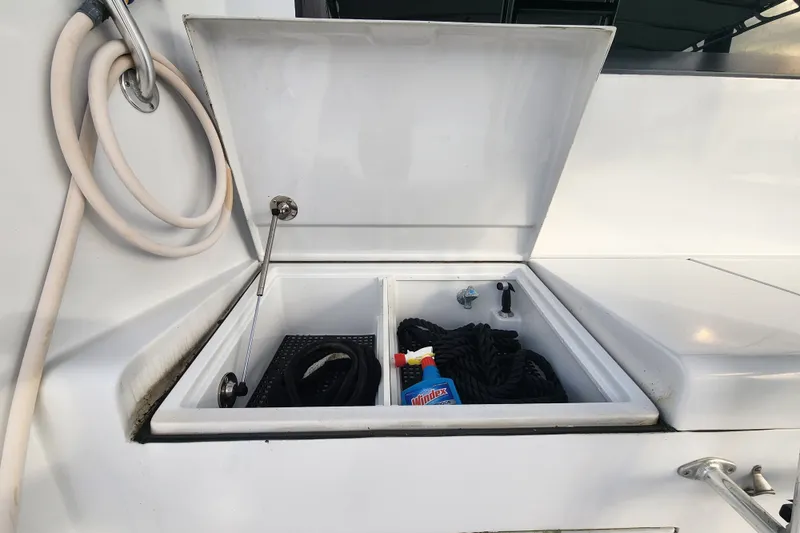 Slide: The Image of Open storage compartment on 1999 Hatteras 65 Convertible yacht with cleaning supplies and ropes. - 66