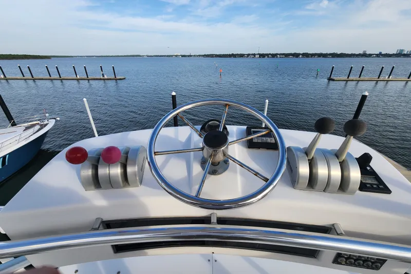 Slide: The Image of Helm of 1999 Hatteras 65 Convertible yacht overlooking calm marina waters. - 56