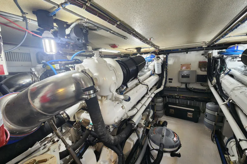 Slide: The Image of Engine room of a 1999 Hatteras 65 Convertible yacht, showcasing mechanical components and piping. - 77