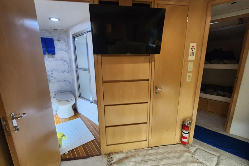 Slide: The Image of 1999 Hatteras 65 Convertible yacht interior with bathroom, TV, and bunk beds. - 18