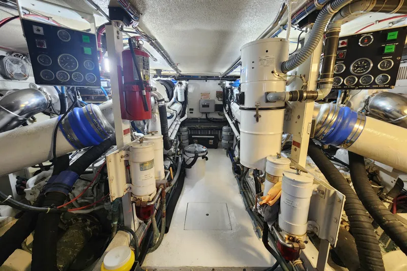 Slide: The Image of Engine room of a 1999 Hatteras 65 Convertible yacht, showcasing machinery and control panels. - 71