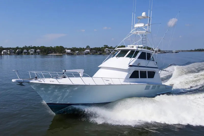 The Image of 1999 Hatteras 65 Convertible yacht cruising on a calm lake under a clear blue sky. - 0