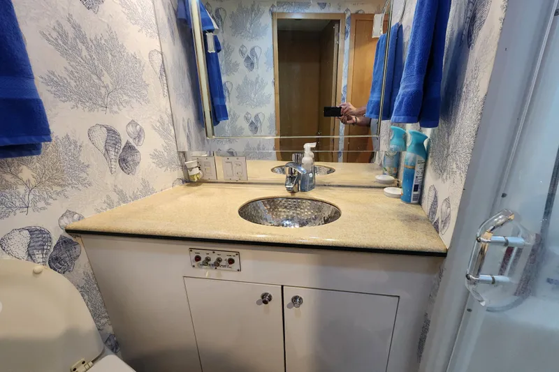 Slide: The Image of Bathroom vanity on 1999 Hatteras 65 Convertible yacht with ocean-themed wallpaper and blue towels. - 27