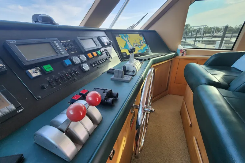 Slide: The Image of Helm of 1999 Hatteras 65 Convertible yacht with navigation controls and leather seating. - 39