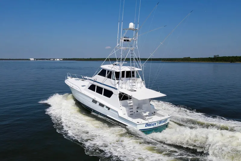 Slide: The Image of 1999 Hatteras 65 Convertible yacht cruising on open water under clear blue skies. - 95