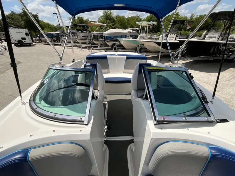 Slide: The Image of A 2011 Sea Ray 185 Sport with a blue sunshade and white-blue seating outdoors. - 14