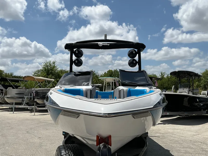 Slide: The Image of A white 2022 Malibu 23LVS boat on a trailer under a cloudy sky. - 2